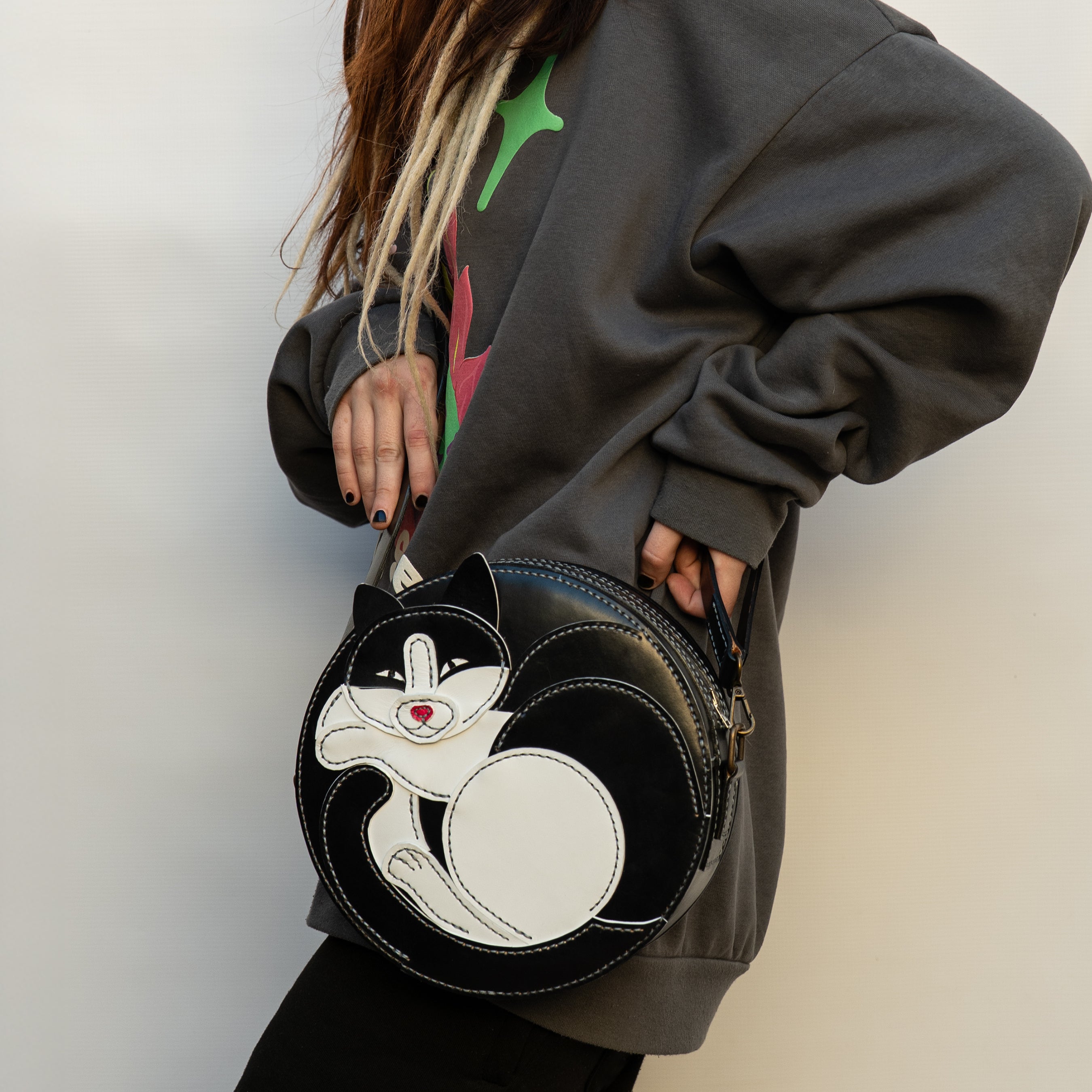 Person holding a black and white cat-shaped bag against a neutral background