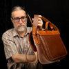 Handmade Morgan Messenger Bag in brown leather with adjustable strap, shown carried by a man against a dark background. Leathercraft design by Vasile and Pavel. View of the back panel.